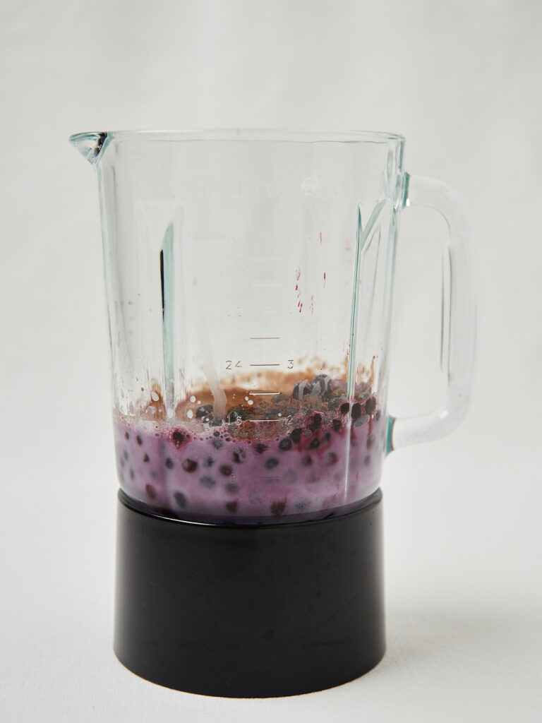 glass mixer with blueberries and almond milk and frozen banana