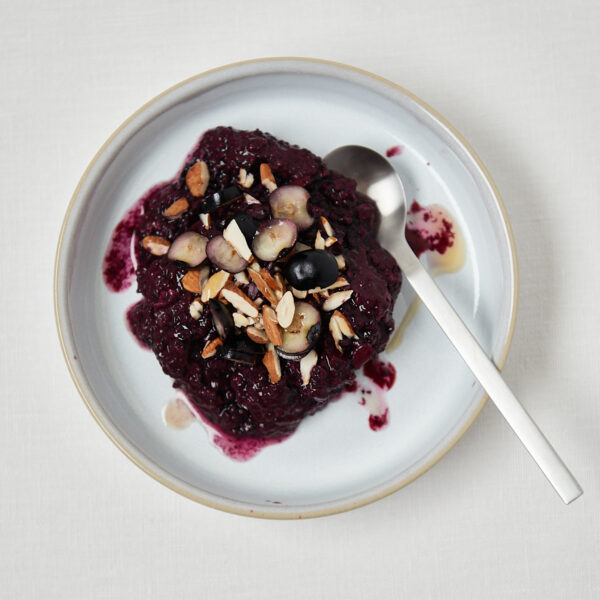 white plate with blueberry oat sliced almonds and a spoon