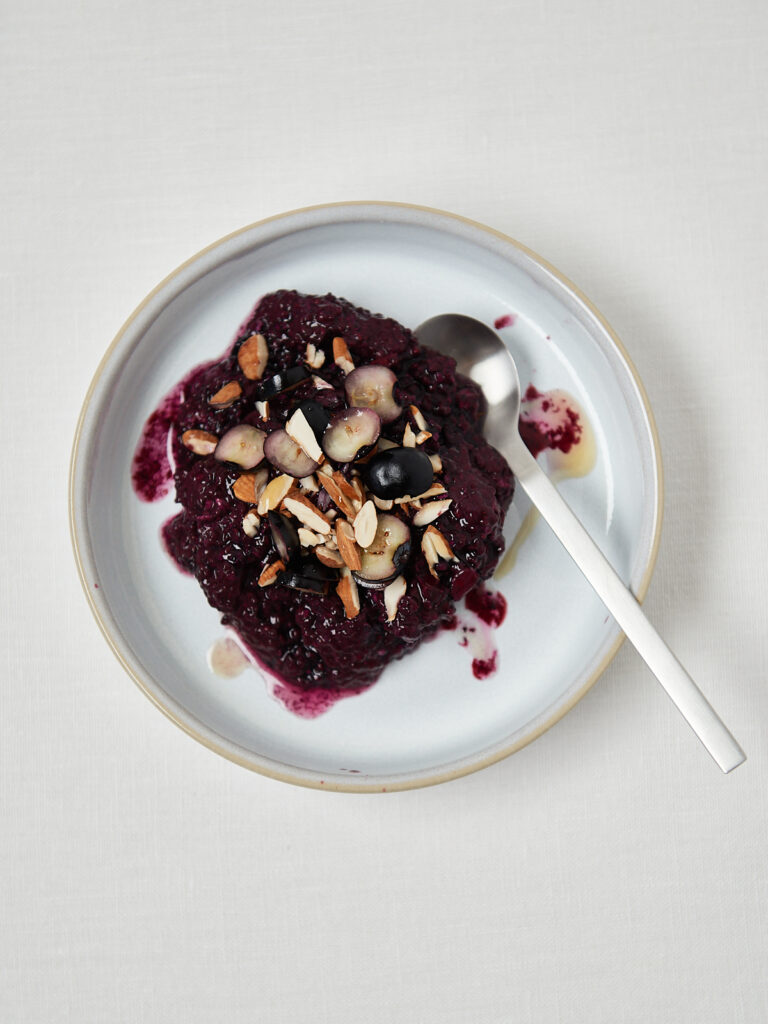 white plate with blueberry oat sliced almonds and a spoon