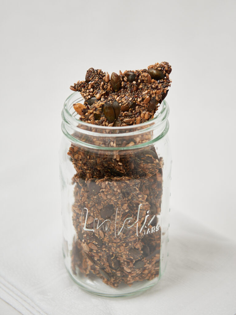 Crunchy fiber and seed crackers stacked vertically in a glass jar