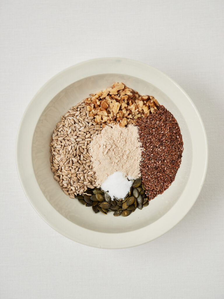 Drei Schalen mit den einzelnen Schritten für das Life-Changing-Bread: trockene Zutaten, vermischte Körnermischung und gebundene, angefeuchtete Brotmasse.