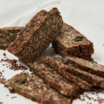 Mehrkorn-Life-Changing-Bread in Scheiben geschnitten, mit sichtbaren Nüssen, Kernen und Samen auf hellem Untergrund.