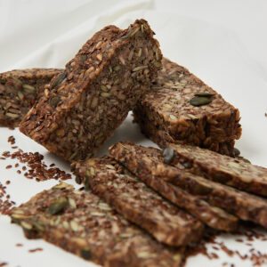 Mehrkorn-Life-Changing-Bread in Scheiben geschnitten, mit sichtbaren Nüssen, Kernen und Samen auf hellem Untergrund.