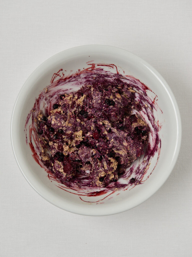 Banana bread batter swirled with thawing berries, creating a purple marbled texture.