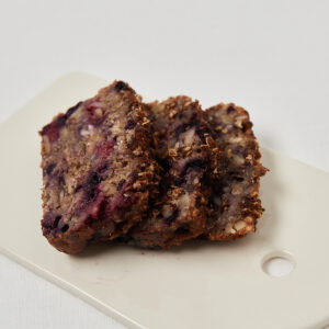 Close-up of a juice very berry banana bread piece served on a white plate.