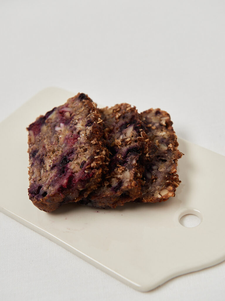Close-up of a juice very berry banana bread piece served on a white plate.