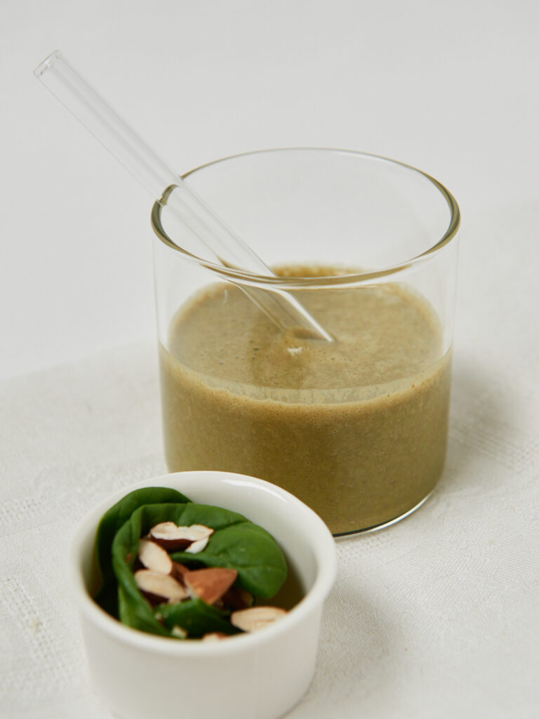 der fertig gemixte, cremige gr&uuml;ne Smoothie im Glas.