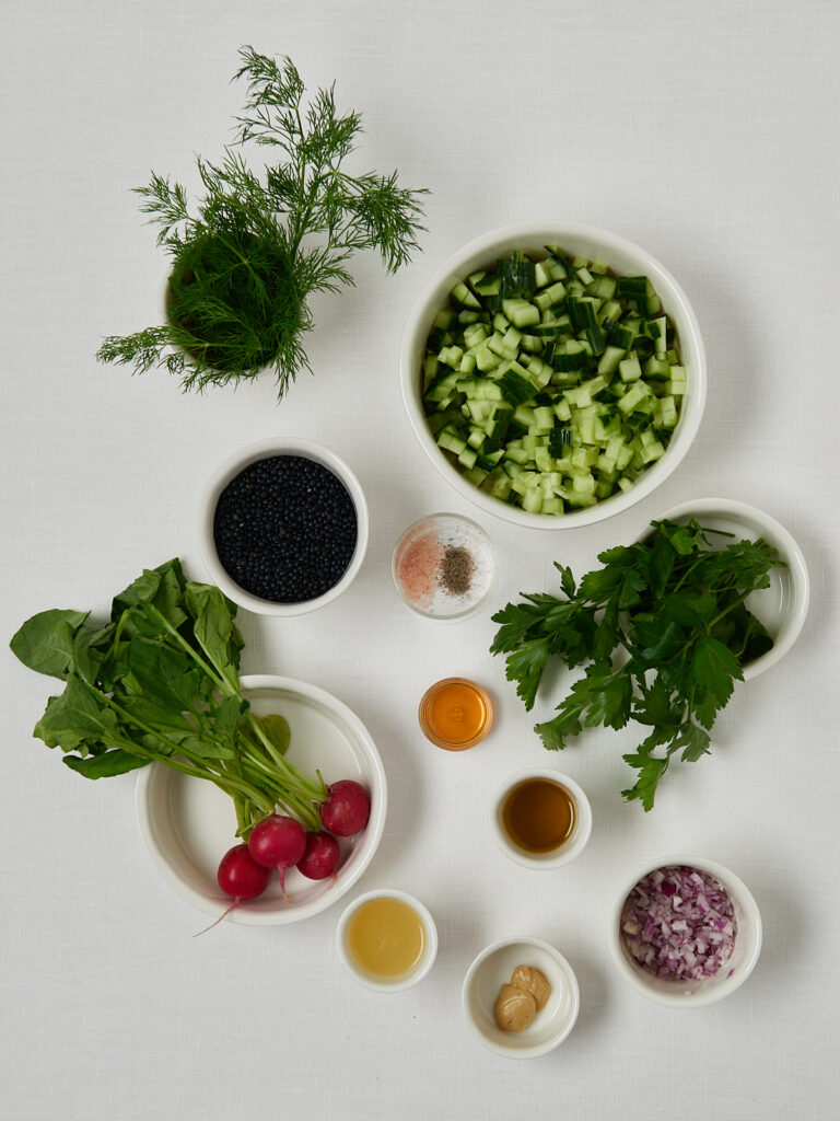 Flatlay mit frischen Zutaten wie Kr&auml;utern, Avocado, Tomaten, Zitronen und Gew&uuml;rzen, ordentlich in kleinen Schalen auf wei&szlig;em Hintergrund arrangiert