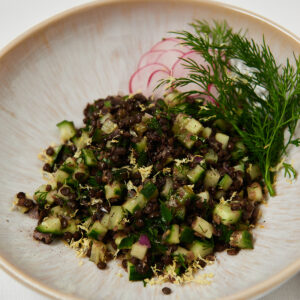 Quinoa and black lentil salad topped with fresh herbs served in a white ceramic bowl.