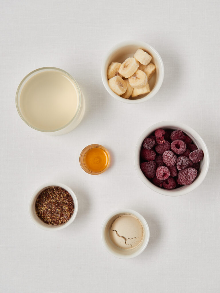small white bowls wih ingredients - frozen bananas, frozen raspberries, almond butter protein poweder
