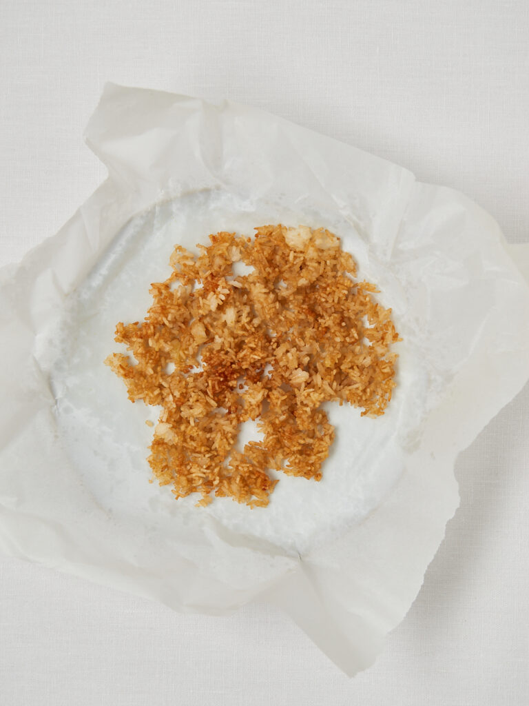 Golden crispy rice spread on parchment paper after air frying.