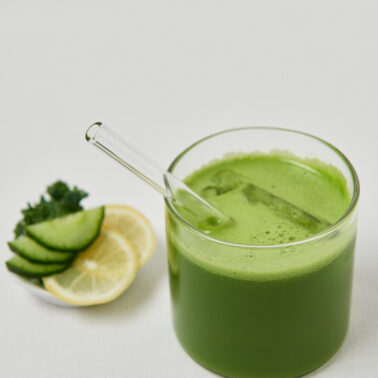 Cremiger gr&uuml;ner Detox-Smoothie im Glas mit Zitronen- und Gurkendeko
