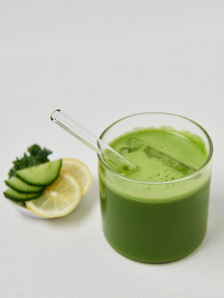 Cremiger gr&uuml;ner Detox-Smoothie im Glas mit Zitronen- und Gurkendeko