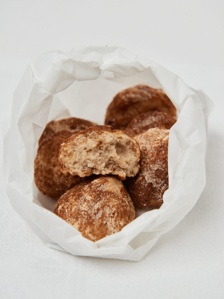 apple munchkins with cinnamon sugar in a white paper bag
