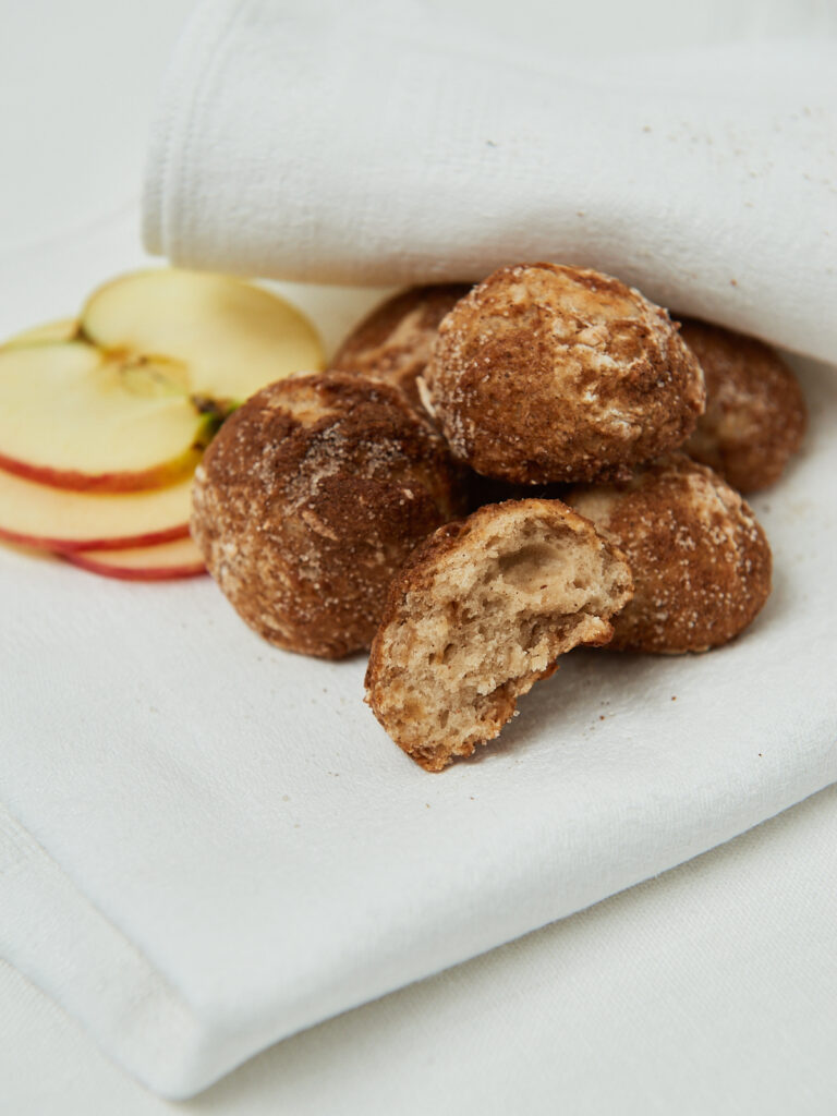 a few apple munchkins with cinnamon sugar and apple slices on the side