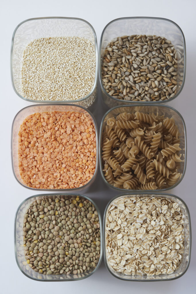 Trockene H&uuml;lsenfr&uuml;chte, Reis und Pasta in Glasbeh&auml;ltern von oben fotografiert.