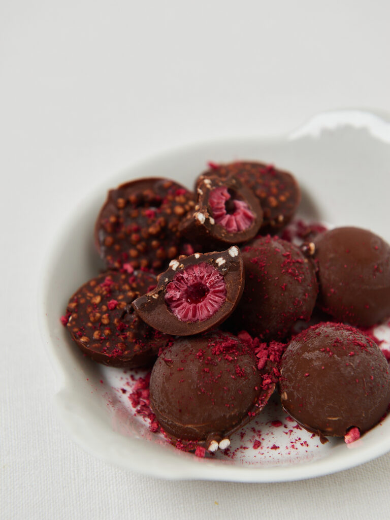 Schokolierte Protein Bites mit Himbeer-Scheiben und Kakaonibs