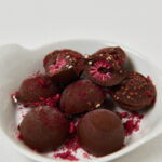 Schokolierte Energy Balls mit gefriergetrockneten Himbeeren in weißer Schale