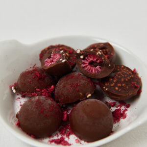 Schokolierte Energy Balls mit gefriergetrockneten Himbeeren in weißer Schale