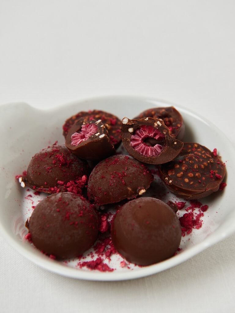 Schokolierte Energy Balls mit gefriergetrockneten Himbeeren in weißer Schale