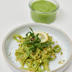 Vegane Pasta mit gr&uuml;nem Pesto und Zitronenscheibe