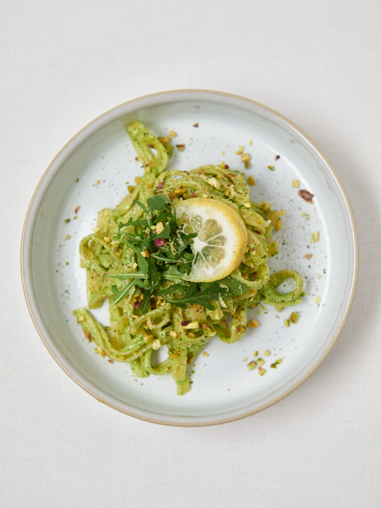 pasta mit gruenem pesto auf weissem teller