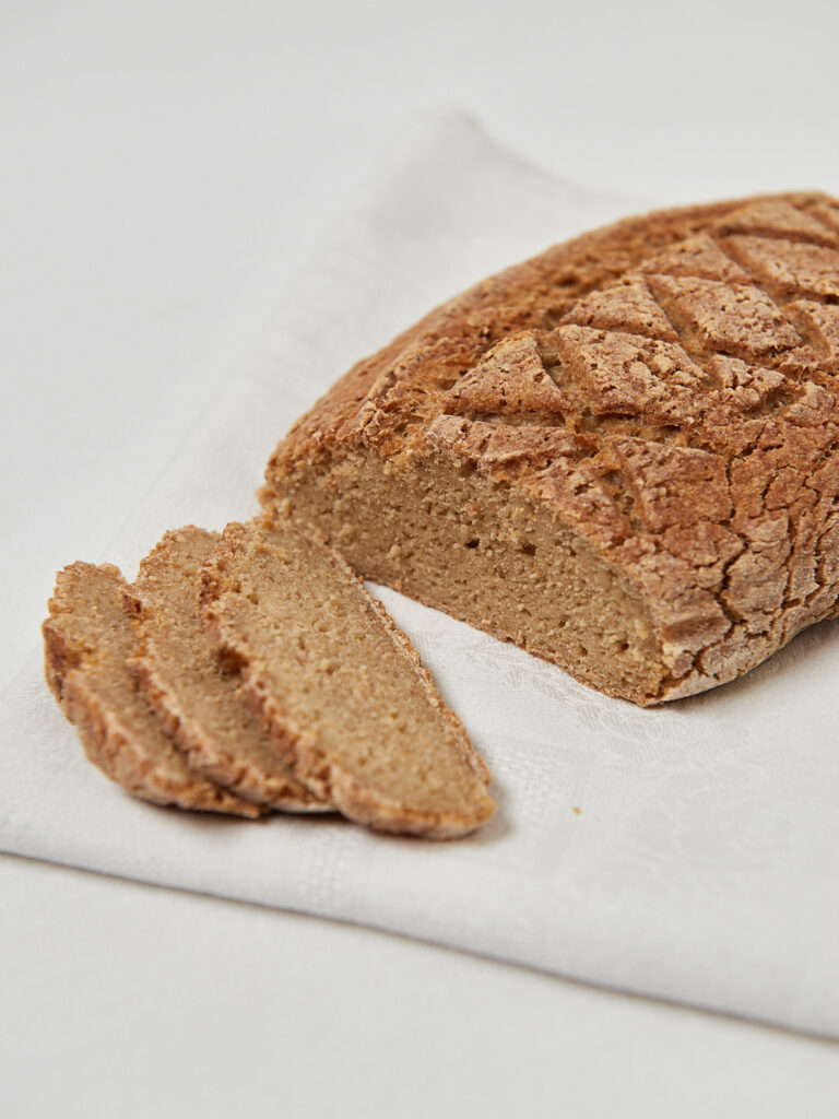 Laib Brot in Scheiben geschnitten auf hellem Untergrund