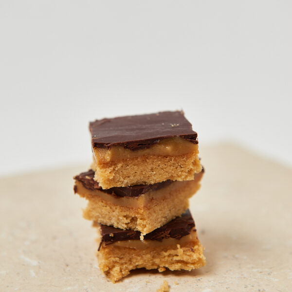 Gestapelte Peanut-Butter-Chocolate Squares auf weißem Teller, cleanes Foodstyling