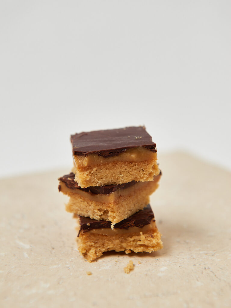 Gestapelte Peanut-Butter-Chocolate Squares auf weißem Teller, cleanes Foodstyling