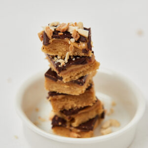 Gestapelte Peanut-Butter-Chocolate Squares auf weißem Teller, cleanes Foodstyling