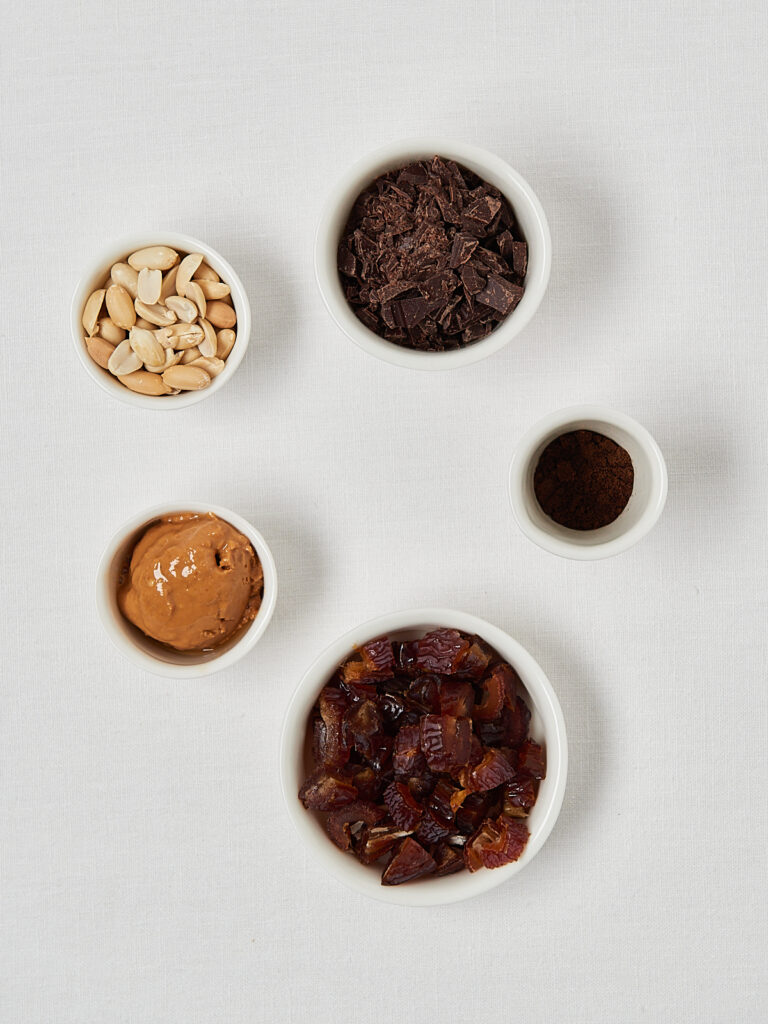 Ingredients for homemade snickers: dates, chocolate, peanut butter, peanuts