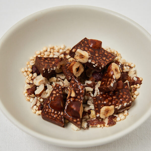Knusprige Schokoladenriegel auf Nuss-Topping, minimalistisches Foodstyling