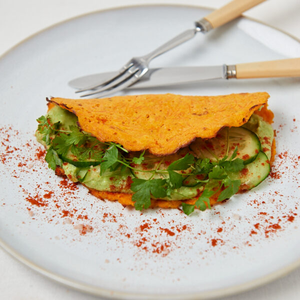 Goldbraun gebackener Gemüsetaler gefüllt mit grünem Salat auf weißem Teller