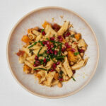 Cremige One-Pan-Pasta mit Kichererbsen, Kürbis, Spinat und Granatapfelkernen in einer hellen Schale