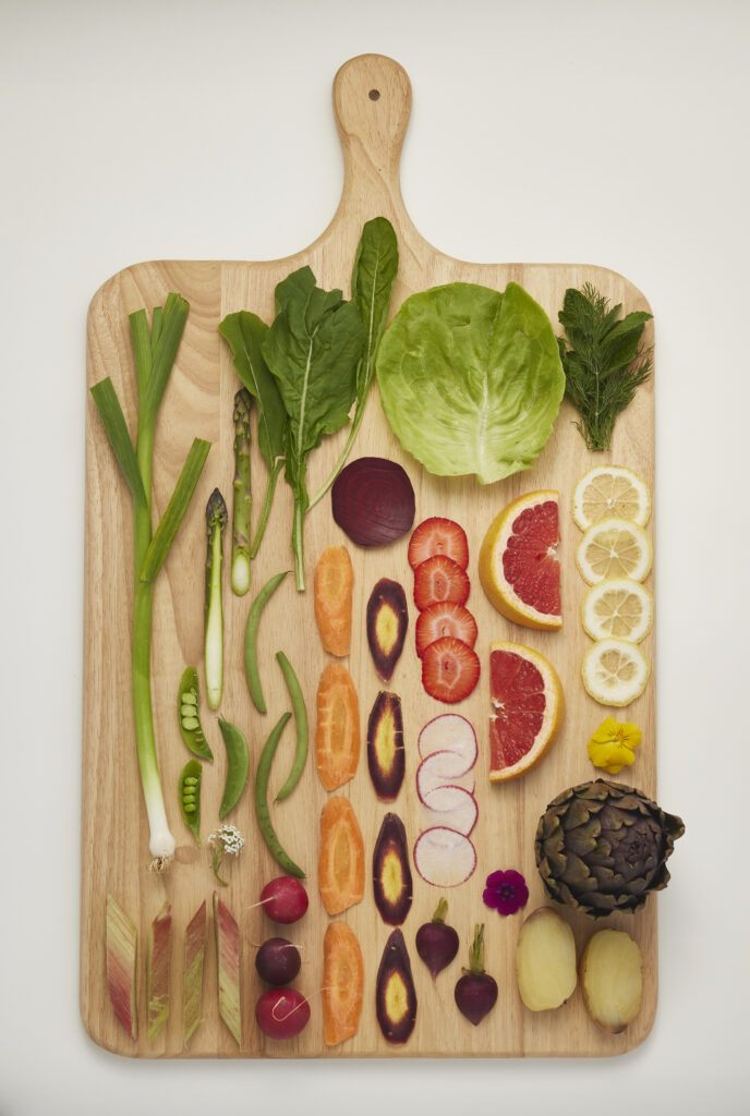 Auswahl an saisonalem Gemüse und Obst auf Holzbrett, natürlich und unverarbeitet.