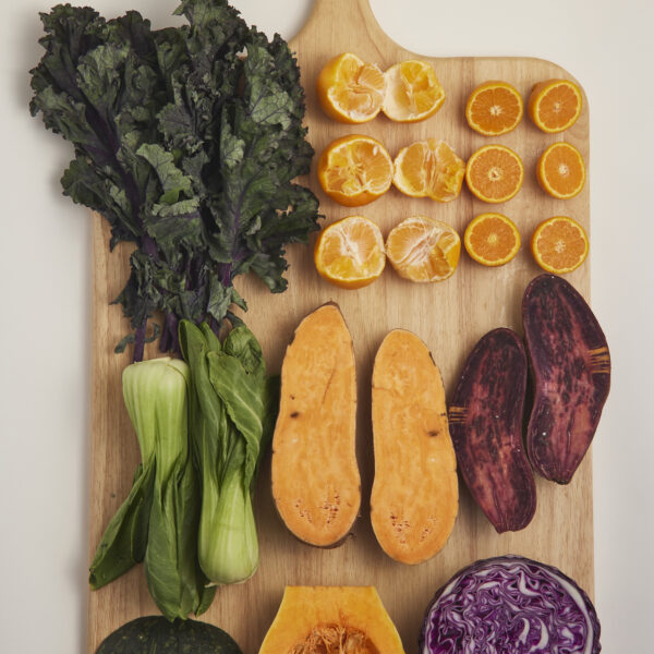 Auswahl an saisonalem Gemüse und Obst auf Holzbrett, natürlich und unverarbeitet.