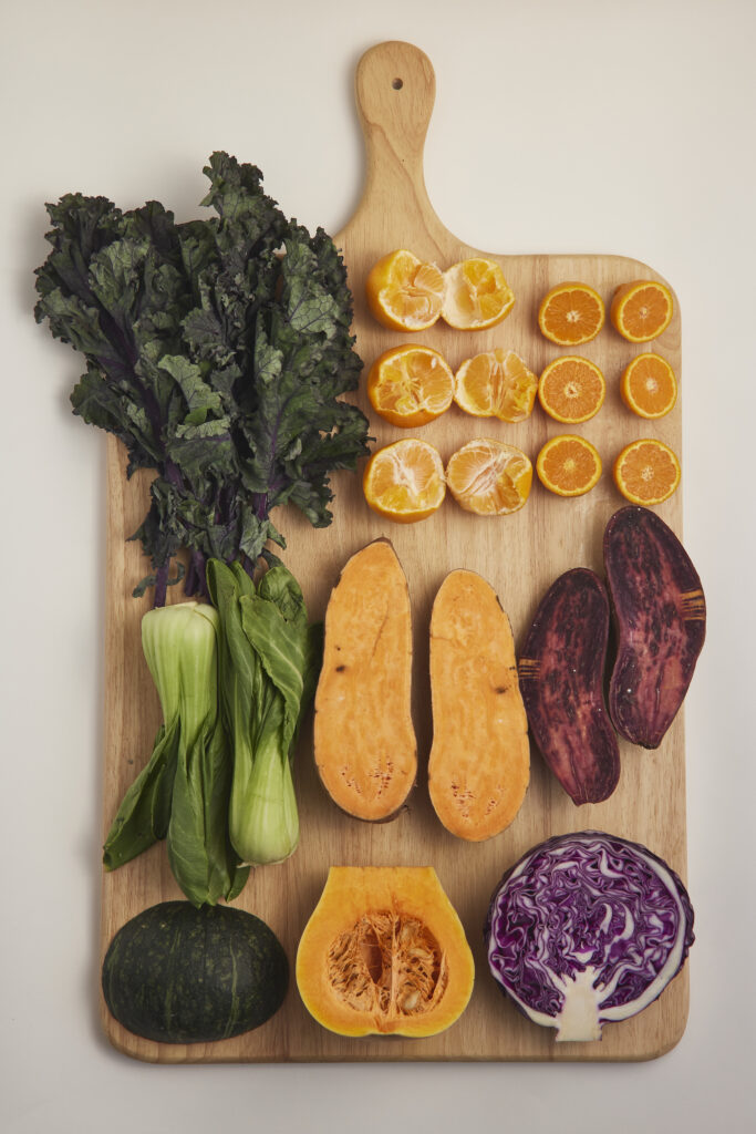 Auswahl an saisonalem Gem&uuml;se und Obst auf Holzbrett, nat&uuml;rlich und unverarbeitet.