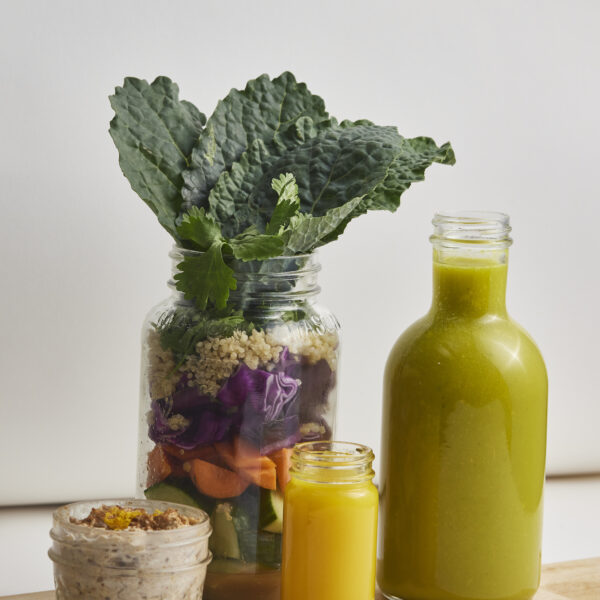 Grüner Saft in Glasflasche mit frischem Grünkohl, Gemüse und Getreide als gesunde Meal-Prep-Inspiration