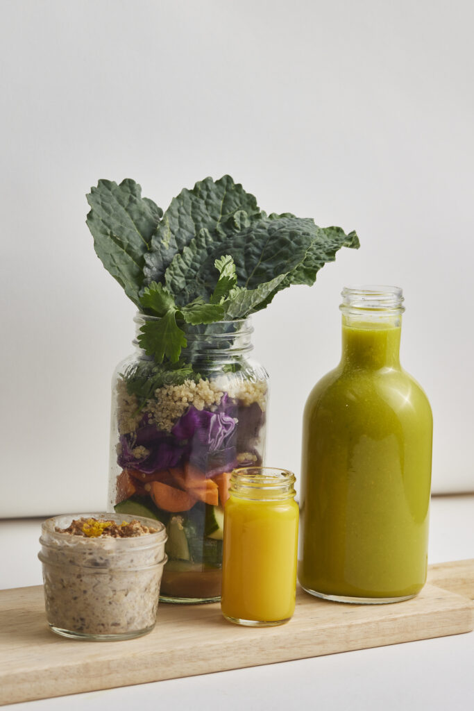 Gr&uuml;ner Saft in Glasflasche mit frischem Gr&uuml;nkohl, Gem&uuml;se und Getreide als gesunde Meal-Prep-Inspiration