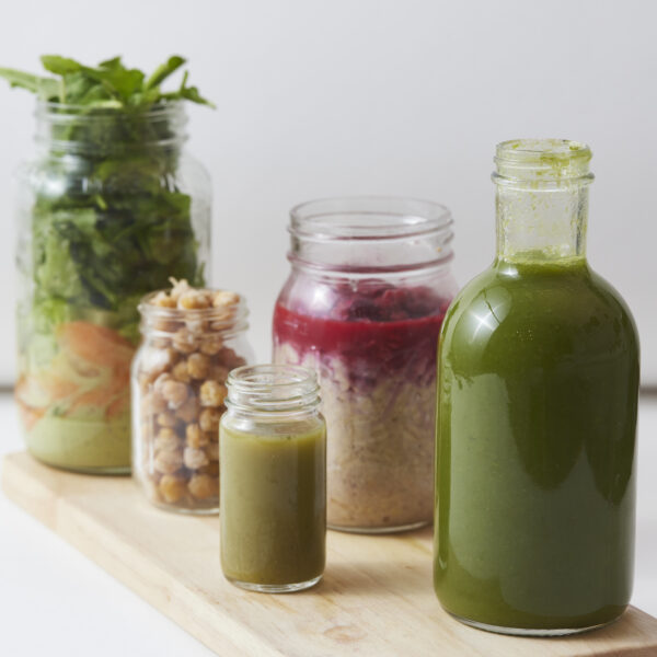 Verschiedene grüne Säfte und Smoothies aus Blattgemüse, Kräutern und Gemüse in Glasgefäßen.