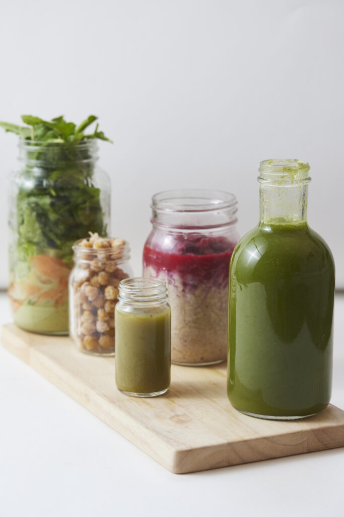 Verschiedene grüne Säfte und Smoothies aus Blattgemüse, Kräutern und Gemüse in Glasgefäßen.