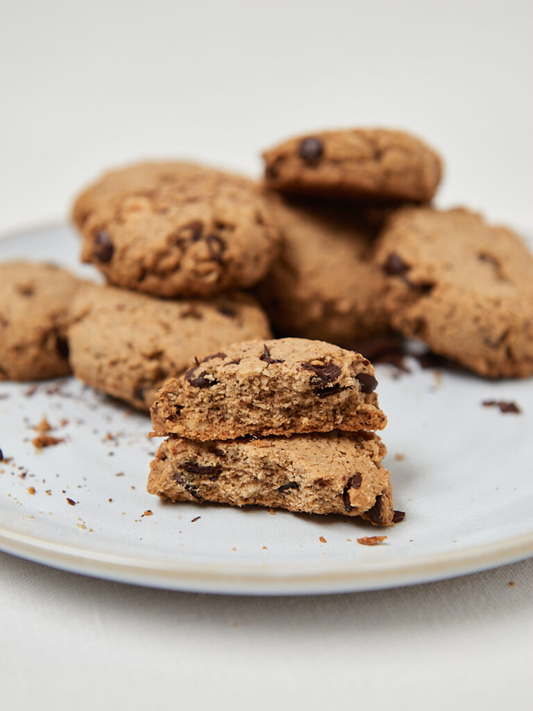 Gluten-free chocolate chip cookies stacked on a white plate, soft baked and macro-friendly