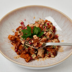 Healthy sweet potato chickpea bowl garnished with parsley on neutral background