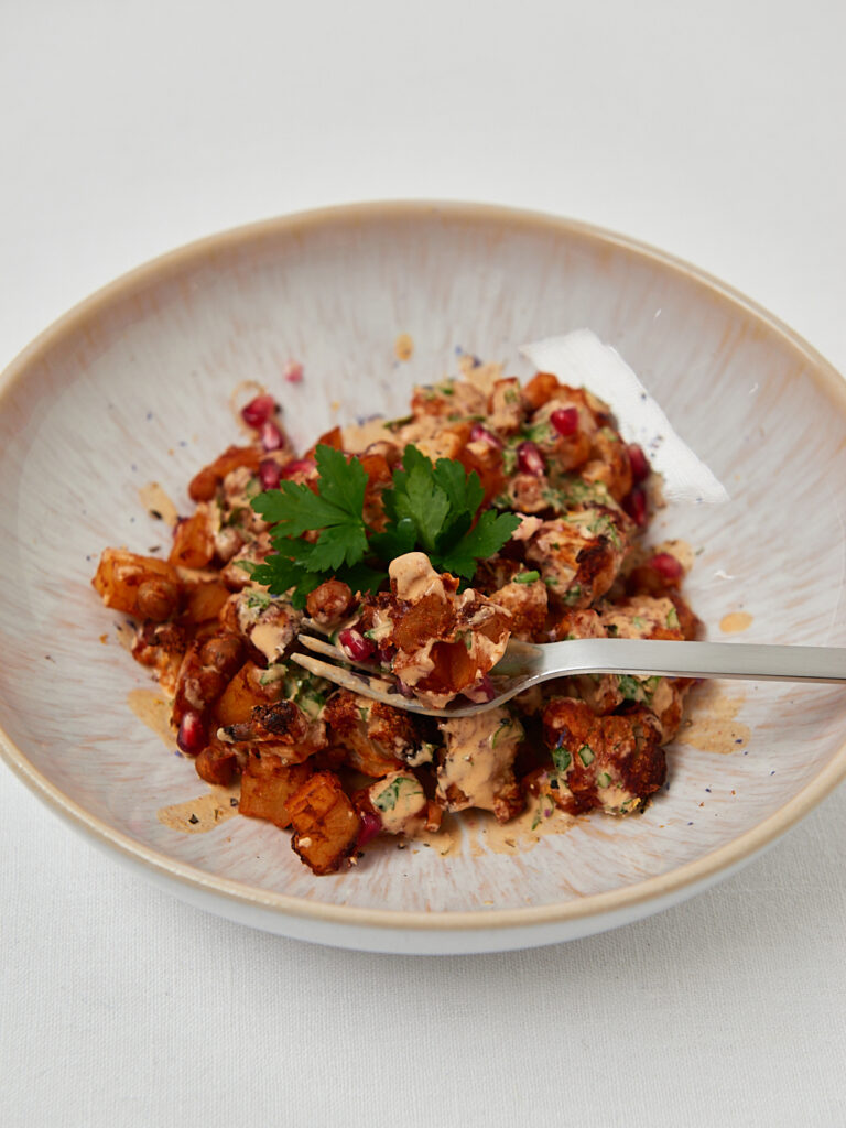 Healthy sweet potato chickpea bowl garnished with parsley on neutral background