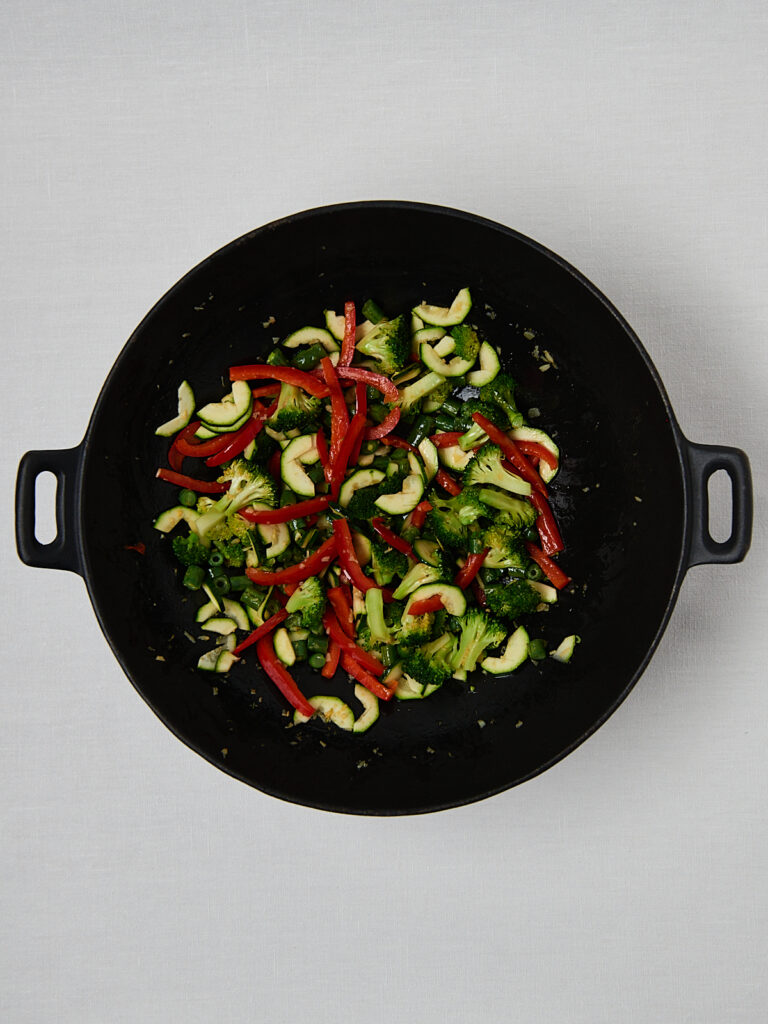 Healthy veggie stir fry cooking in skillet, plant based meal prep