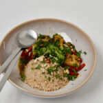 Top view of wholesome veggie bowl with brown rice and fresh herbs