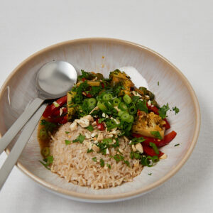 Top view of wholesome veggie bowl with brown rice and fresh herbs