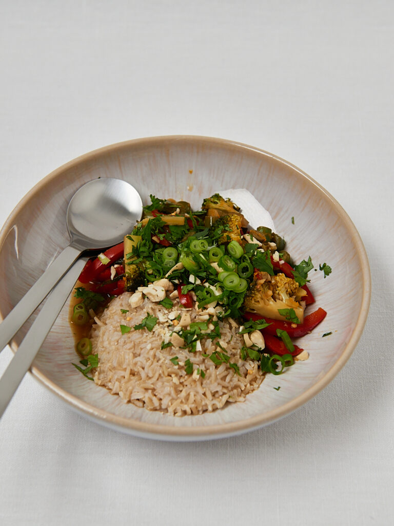 Top view of wholesome veggie bowl with brown rice and fresh herbs