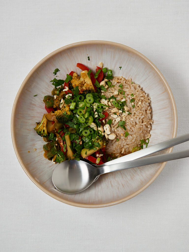 Healthy grain bowl with saut&eacute;ed vegetables and herbs on white plate