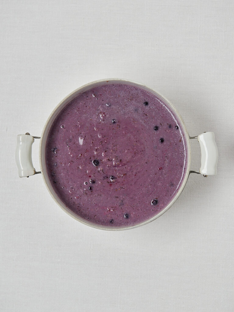 Glattes lila Porridge in wei&szlig;em Topf &ndash; schlichte Overhead-Aufnahme